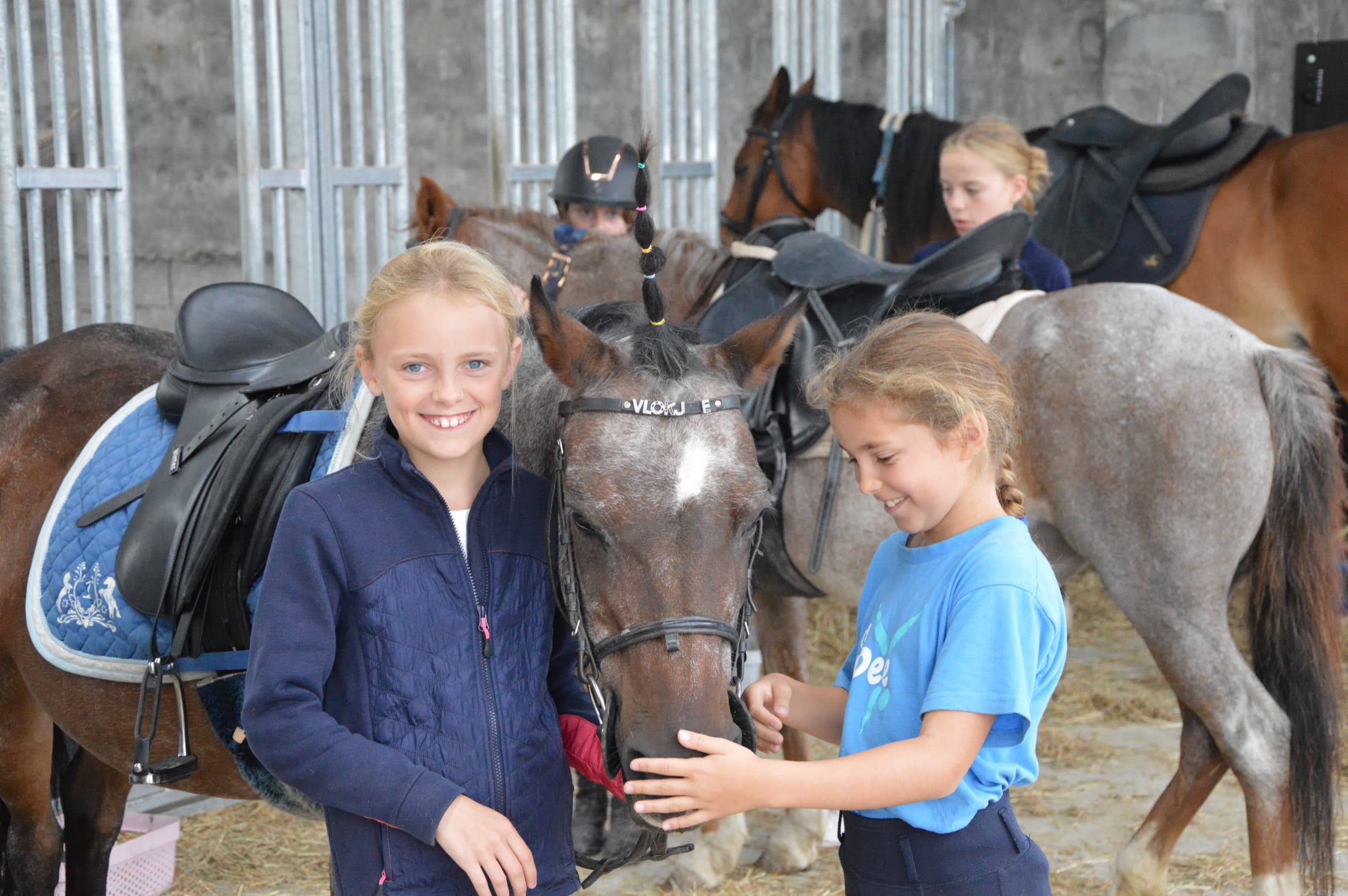 Kinderen krijgen rijles op pony's tijdens een ponykamp