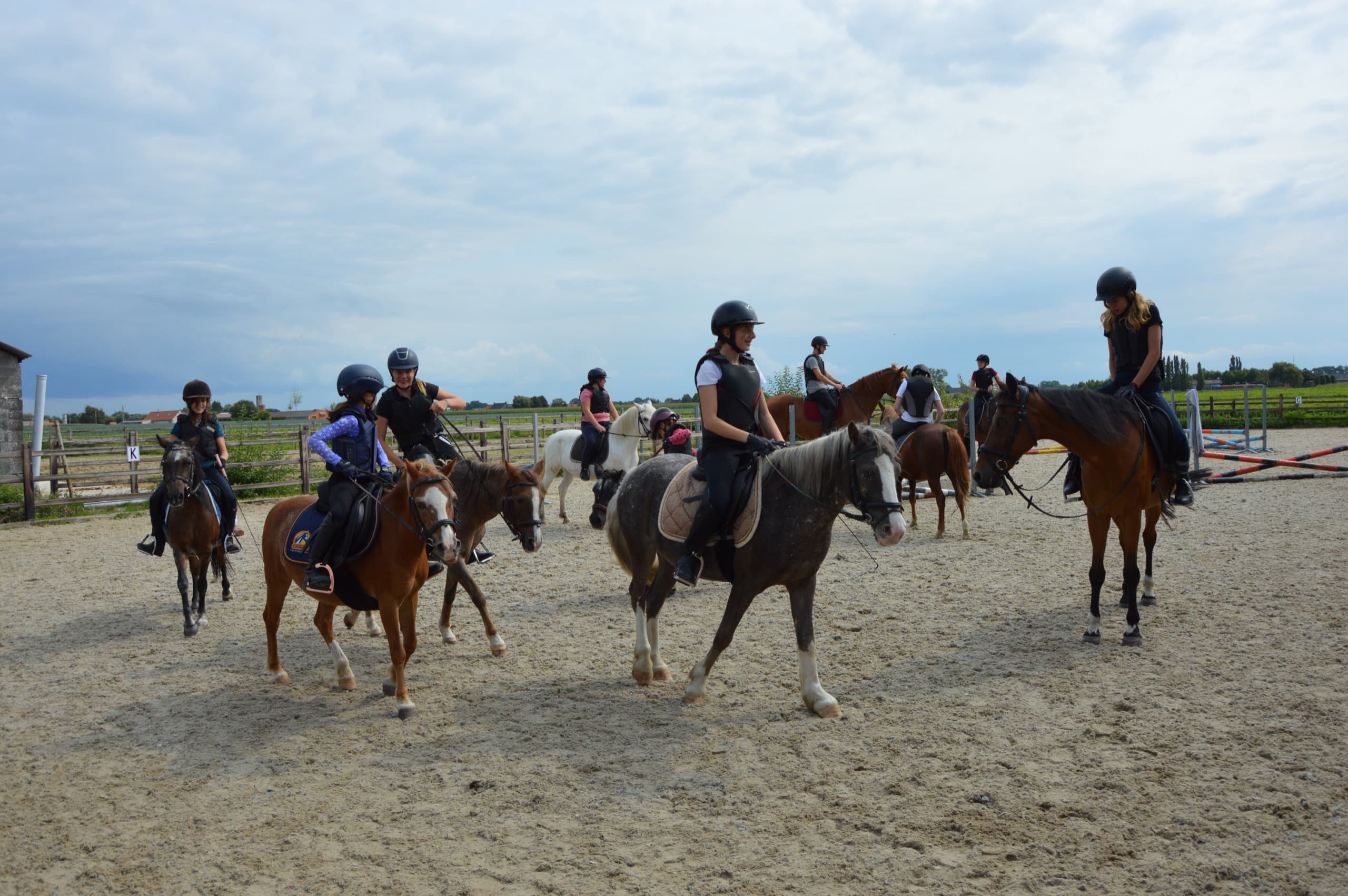 Kind springt over een hindernis op een pony tijdens de rijles